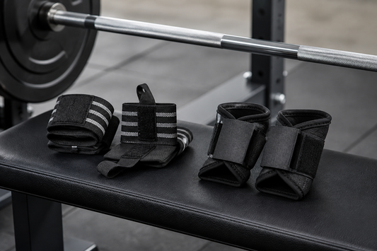 Flexible wrist wraps and more structured wrist supports arranged side by side on a weightlifting bench
